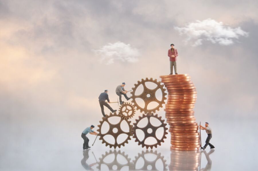 Miniature,Businessman,On,Top,Of,A,Pile,Of,Coins,With