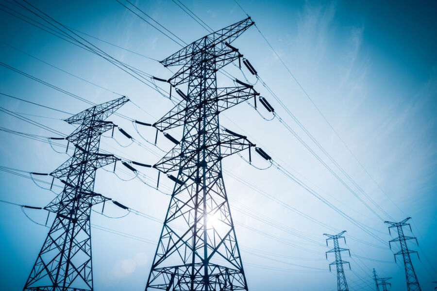 Electricity,Transmission,Pylon,Silhouetted,Against,Blue,Sky,At,Dusk